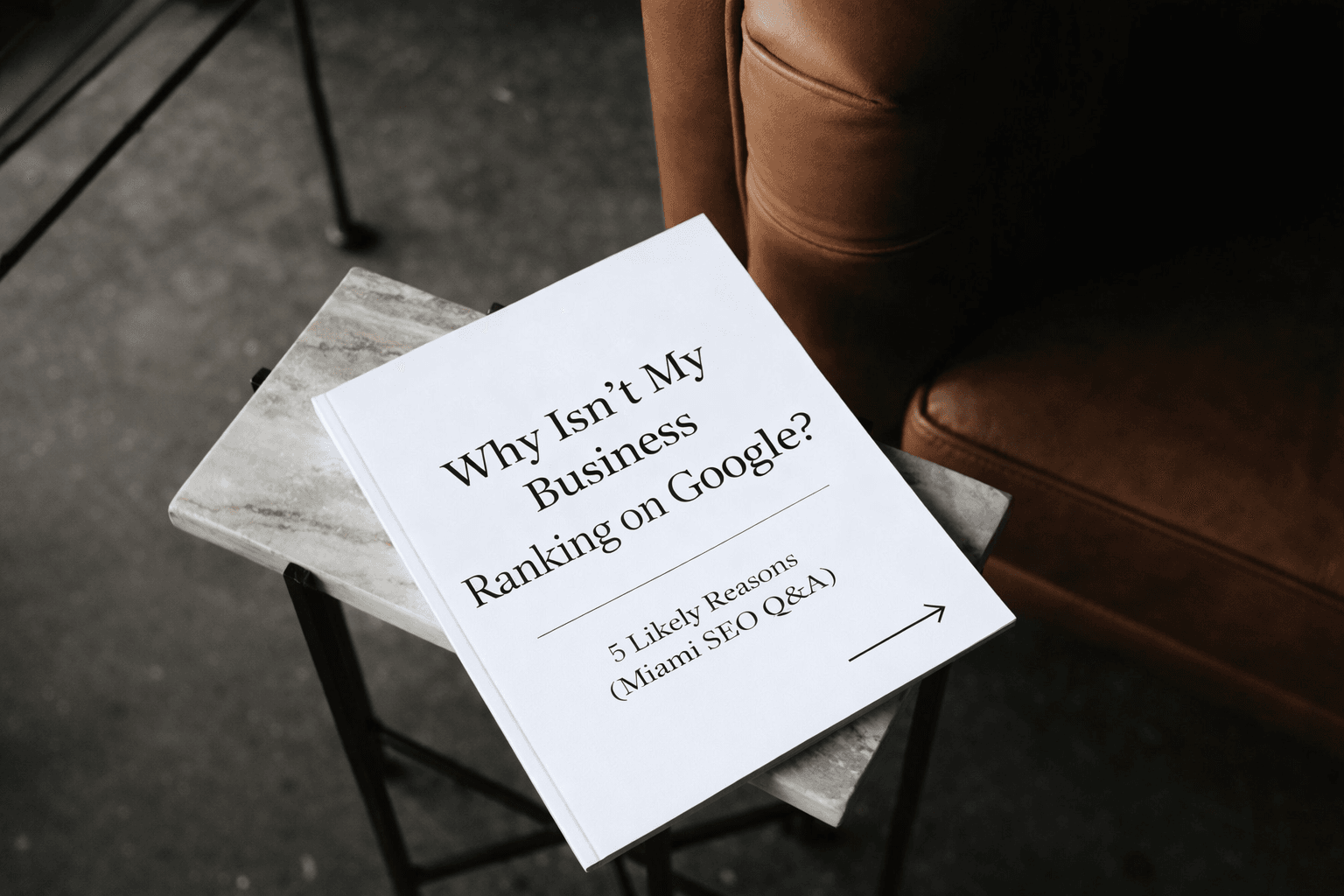 Booklet on a marble side table titled ‘Why Isn’t My Business Ranking on Google? 5 Likely Reasons (Miami SEO Q&A)’.
